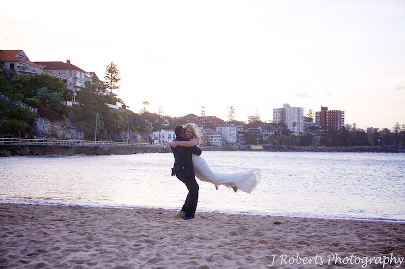 Groom swinging bride in the air on Shelley Beach - wedding photography sydney